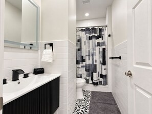 A bathroom with a white sink, black towel holder, and a black makeup bag.
