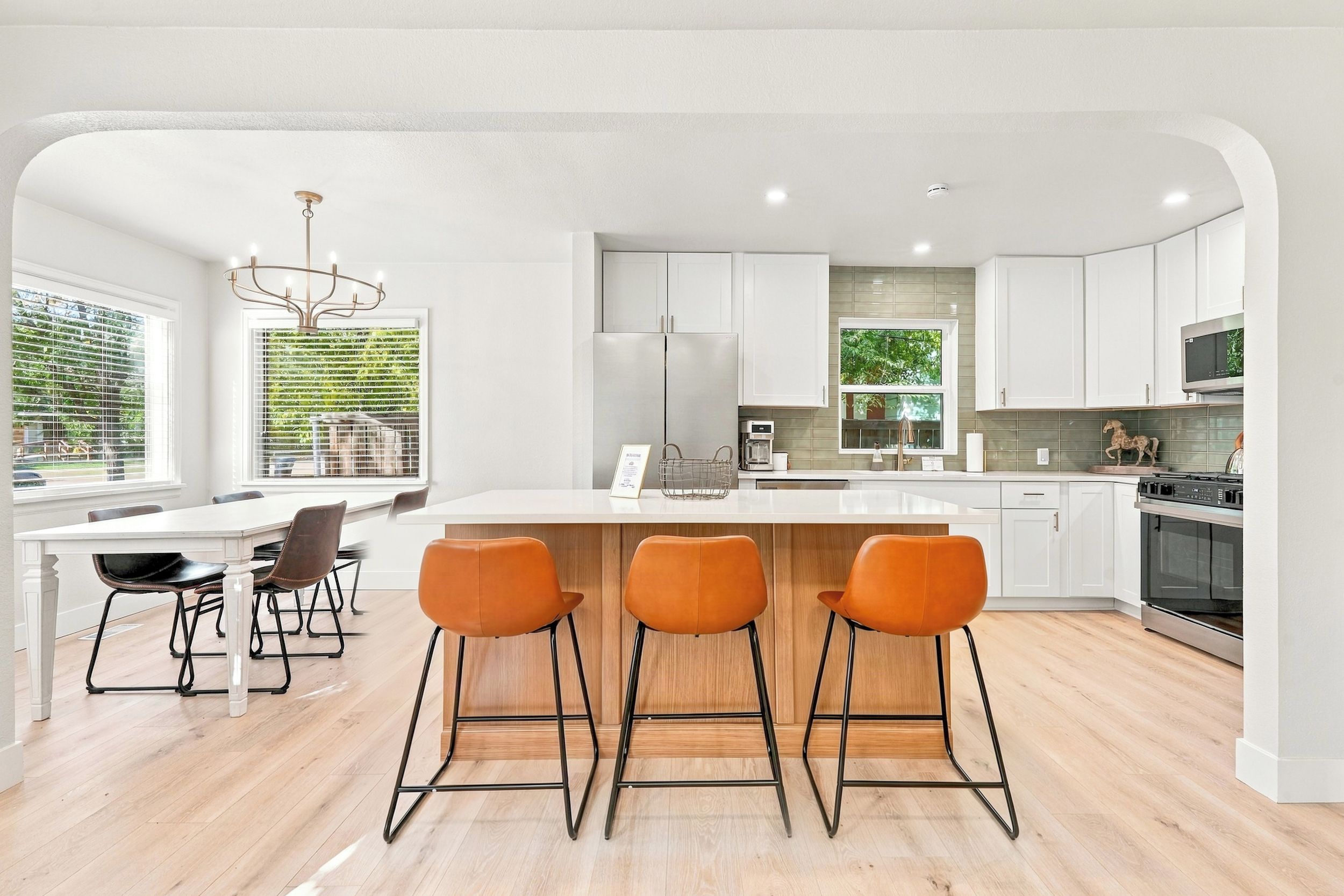 Una cocina moderna con una isla central, taburetes de bar y una zona de comedor con sillas.