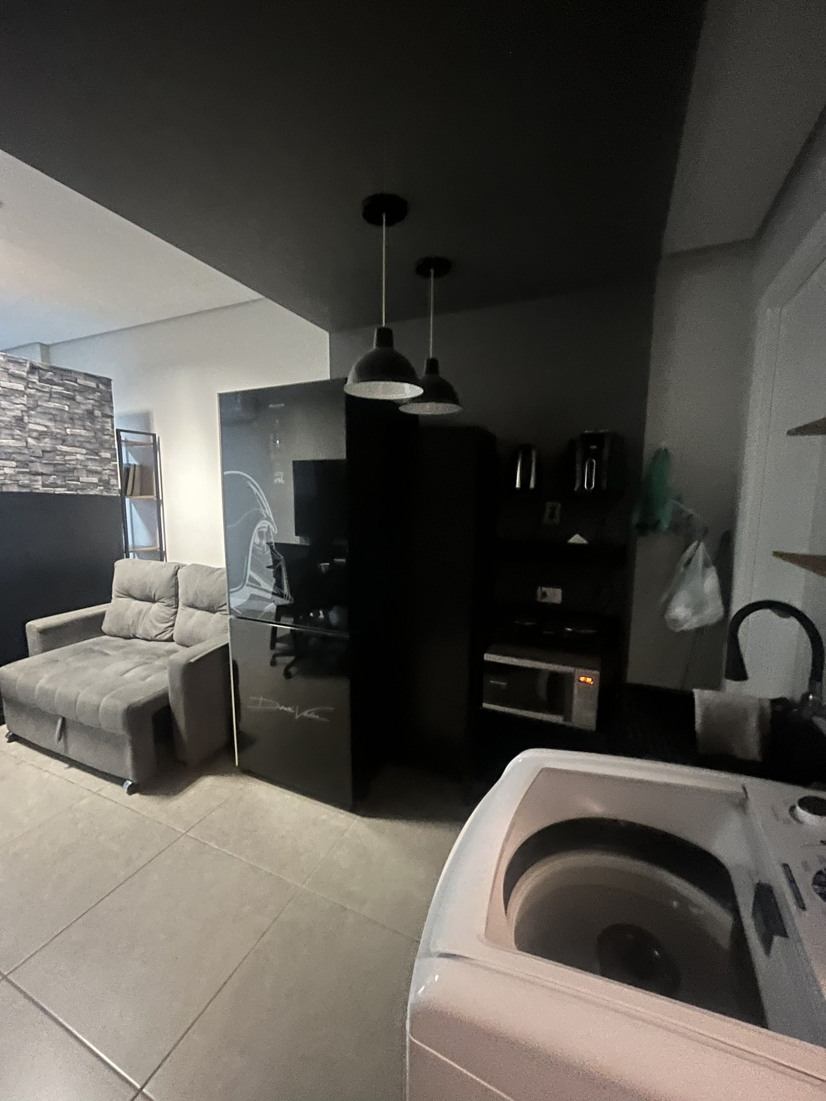 A compact living space with a sofa, a kitchenette, and a small bathroom.