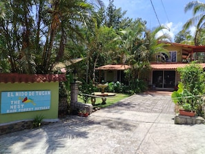 Ein tropisches Refugium mit einem Schild, auf dem 'El Nido de Tucan The Nest Rain Forest Retreat' steht.