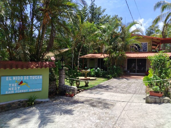 Ein tropisches Refugium mit einem Schild, auf dem 'El Nido de Tucan The Nest Rain Forest Retreat' steht.