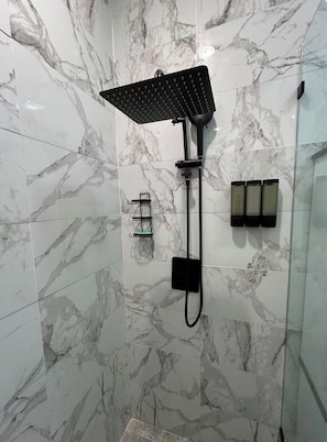 Un baño con ducha, toallero y dispensador de jabón.
