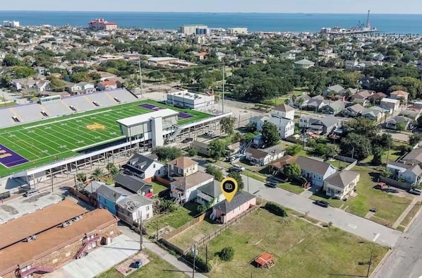Vista aérea de un barrio residencial con un gran campo deportivo y un edificio moderno de techo plano.