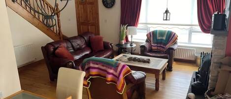 Un salon comprenant un canapé, un fauteuil, une table basse et un plaid à motifs.