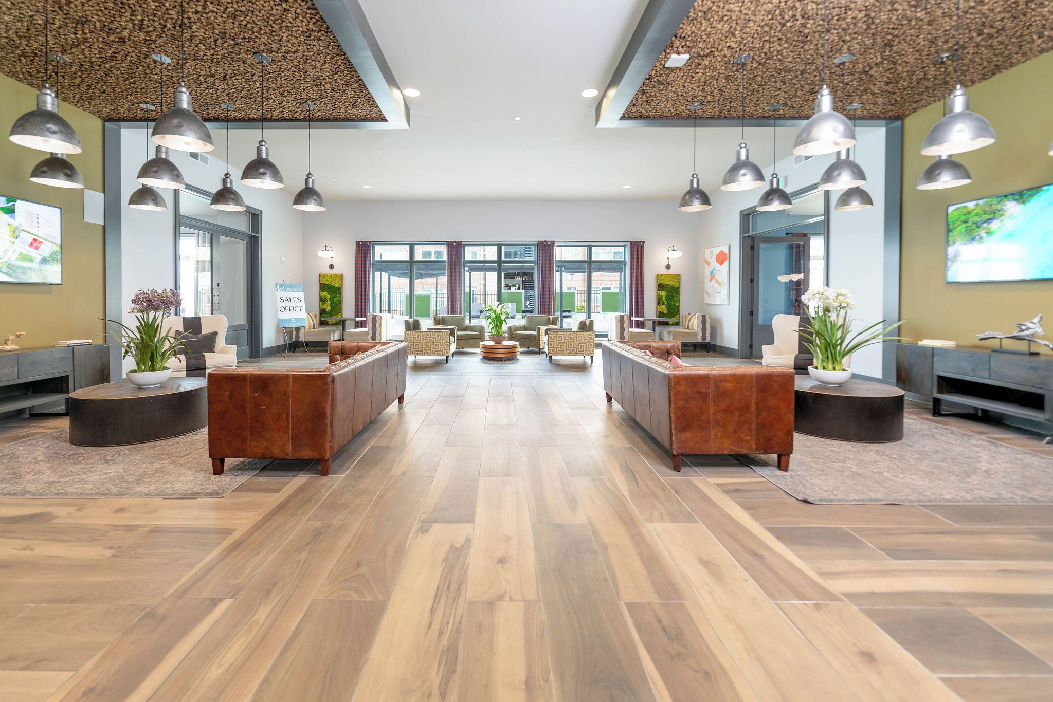 A spacious lobby with a central reception desk, multiple seating areas, and a high ceiling with hanging lights.