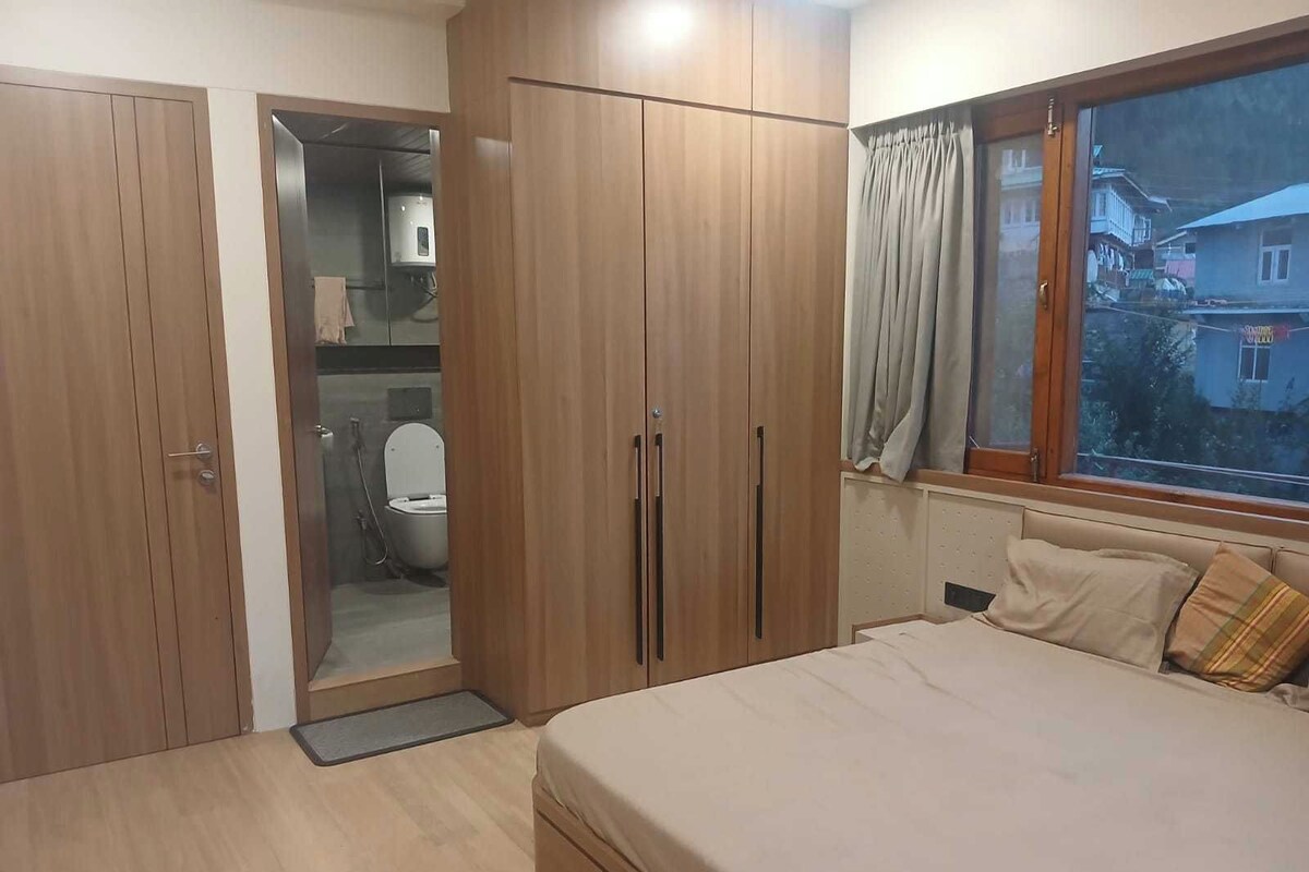 Ein Schlafzimmer mit einem Bett, einem Holzschrank und einem Fenster mit Vorhängen.