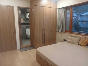 Ein Schlafzimmer mit einem Bett, einem Holzschrank und einem Fenster mit Vorhängen.