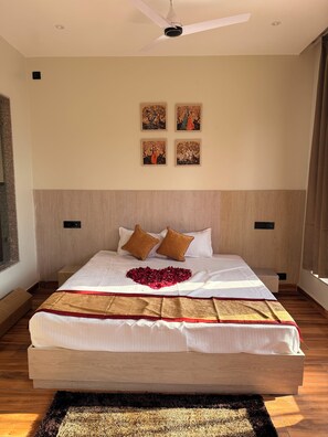 Une chambre à coucher avec un grand lit, un ventilateur de plafond et quatre tableaux encadrés accrochés au mur.