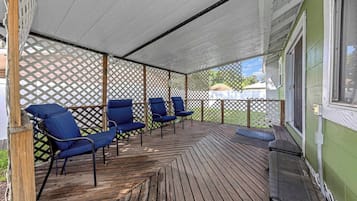A covered outdoor seating area with wooden flooring and blue chairs.
