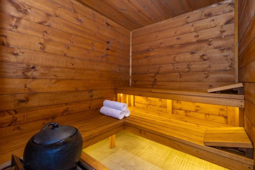 A wooden sauna with benches and a large container, likely for water or steam.