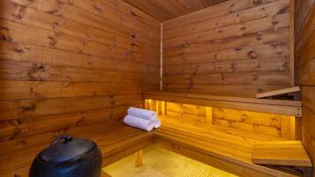 A wooden sauna with benches and a large container, likely for water or steam.
