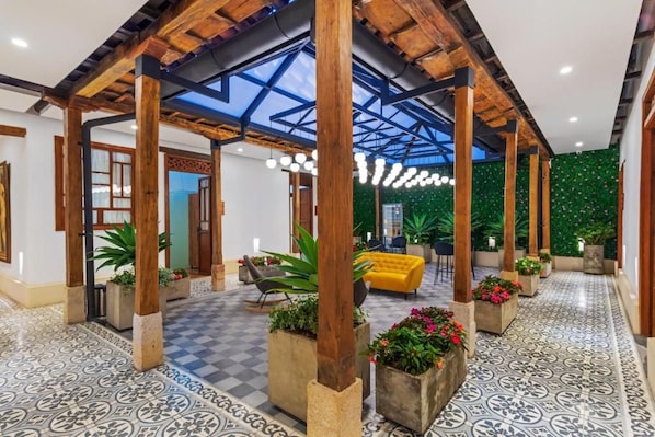 A spacious lobby with a high ceiling, wooden beams, and a checkered floor pattern.