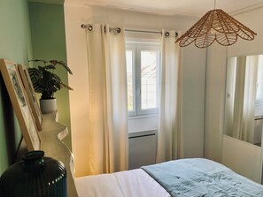 A bedroom with a bed, a window with curtains, a hanging light fixture, and a potted plant. - New Listing (Pontenx-les-Forges)