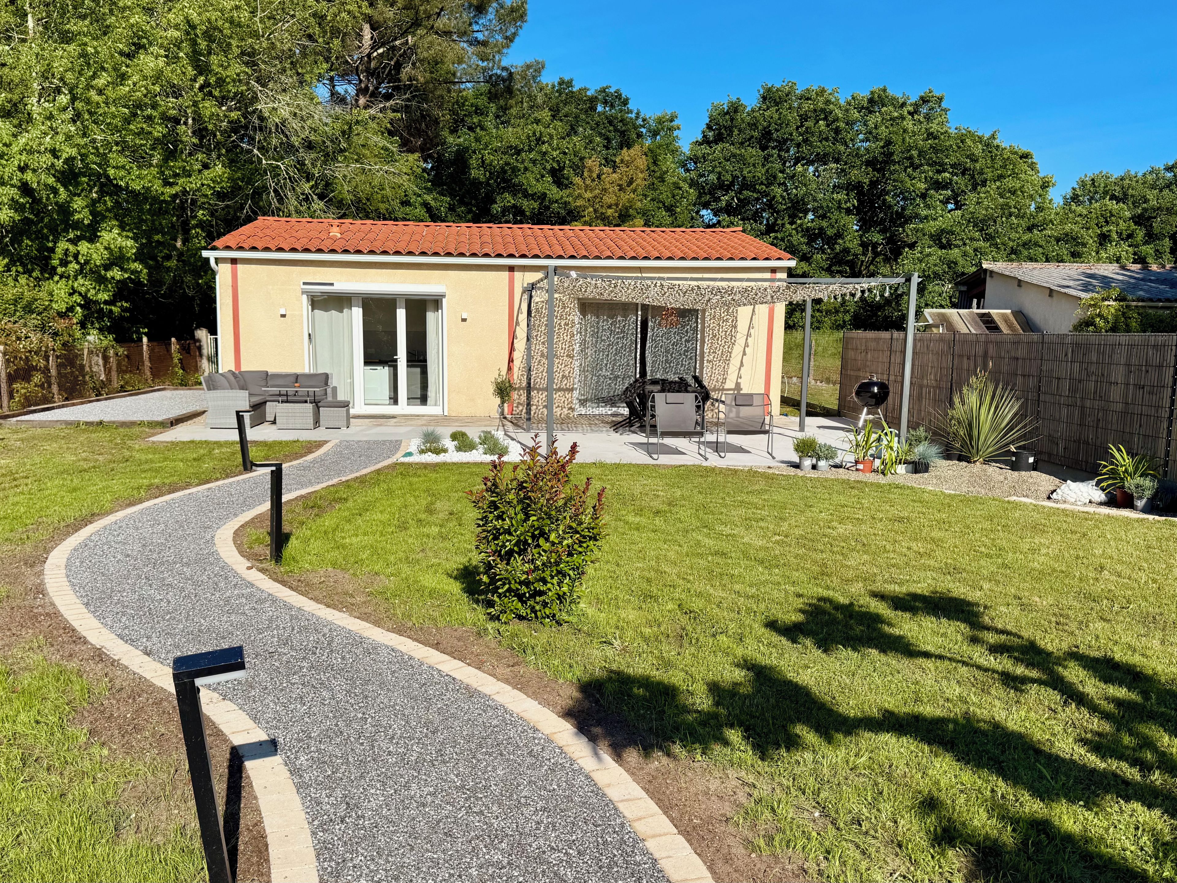 A residential property with a patio, outdoor seating, and a gravel driveway.