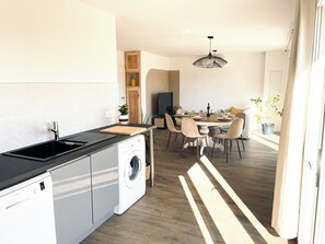 A modern kitchen with a Bosch washing machine, a dining area with a round table and chairs, and a hanging light fixture. - New Listing (Pontenx-les-Forges)