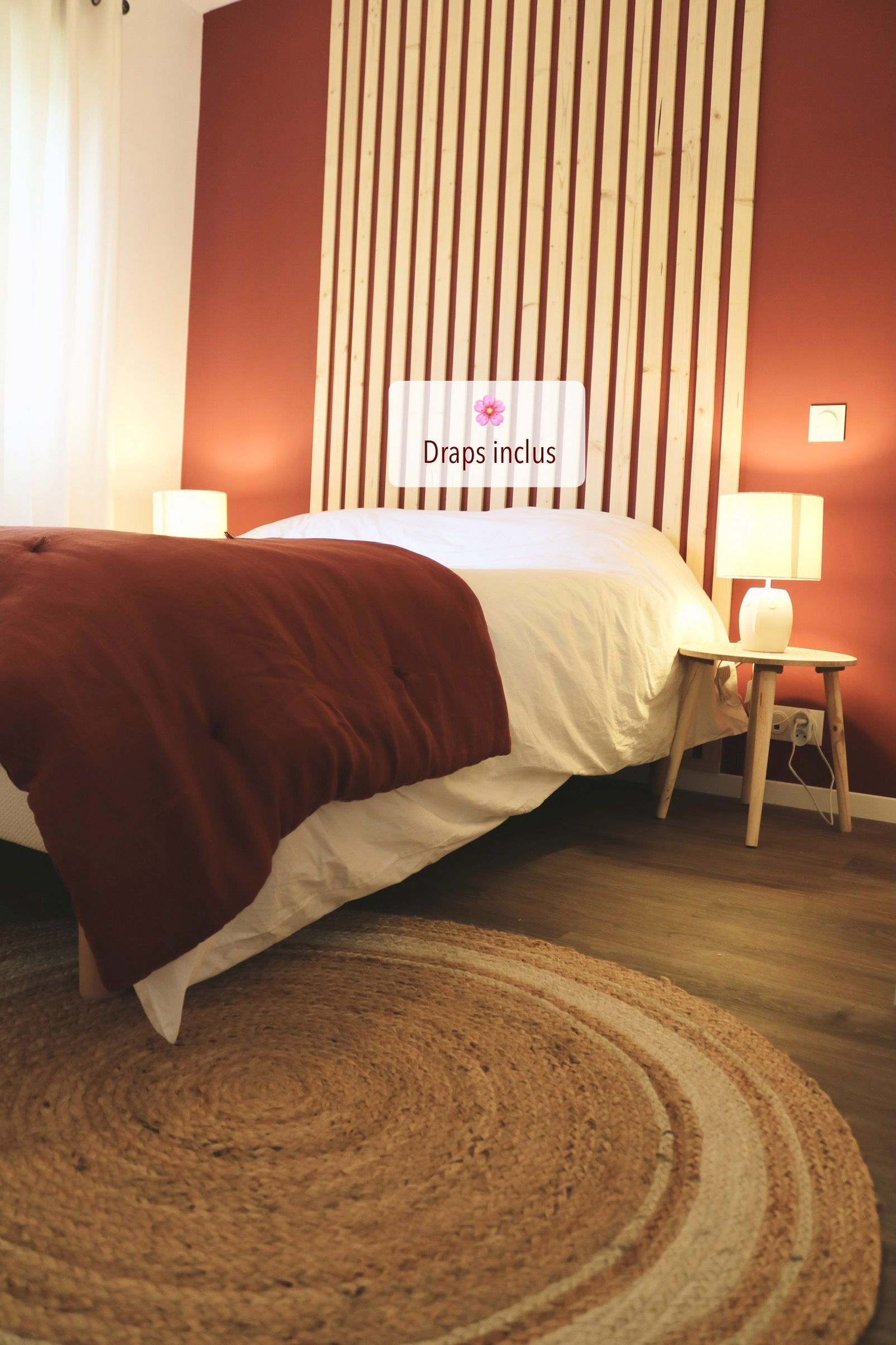 A bedroom with a bed, a bedside table with a lamp, and a wall with vertical wooden slats.