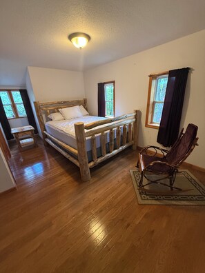 A bedroom with a wooden bed, a chair, and a window. - Peaceful getaway in Amish Country (Clare)