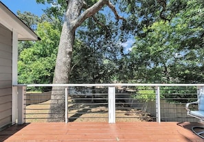 A covered outdoor area with a wooden deck, a metal railing, and a bench.
