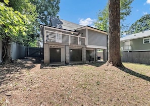 A two-story house with a covered patio area and a fenced backyard.