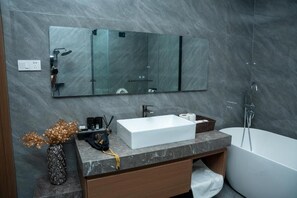 Un baño moderno con un espejo grande, un lavabo blanco, una bañera y una encimera de mármol.