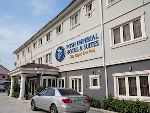 Un hôtel avec une enseigne indiquant : « Posh Imperial Hotel & Suites, séjournez comme des rois, vivez avec élégance ».