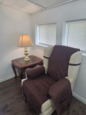 A room with a single armchair, a small wooden side table with a lamp, and a window with blinds. - 3 bdrm house! Unbeatable Location! Close to Everything: Wind Rock, Melton Hill! (Clinton)