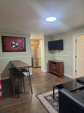 A modern kitchen with a wooden table and stools, a refrigerator, and a TV mounted on the wall. - 3 bdrm house! Unbeatable Location! Close to Everything: Wind Rock, Melton Hill! (Clinton)