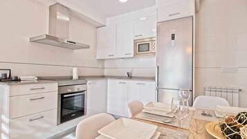 Una cocina moderna con armarios blancos, horno integrado y microondas.