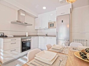 Una cocina moderna con armarios blancos, horno integrado y microondas.