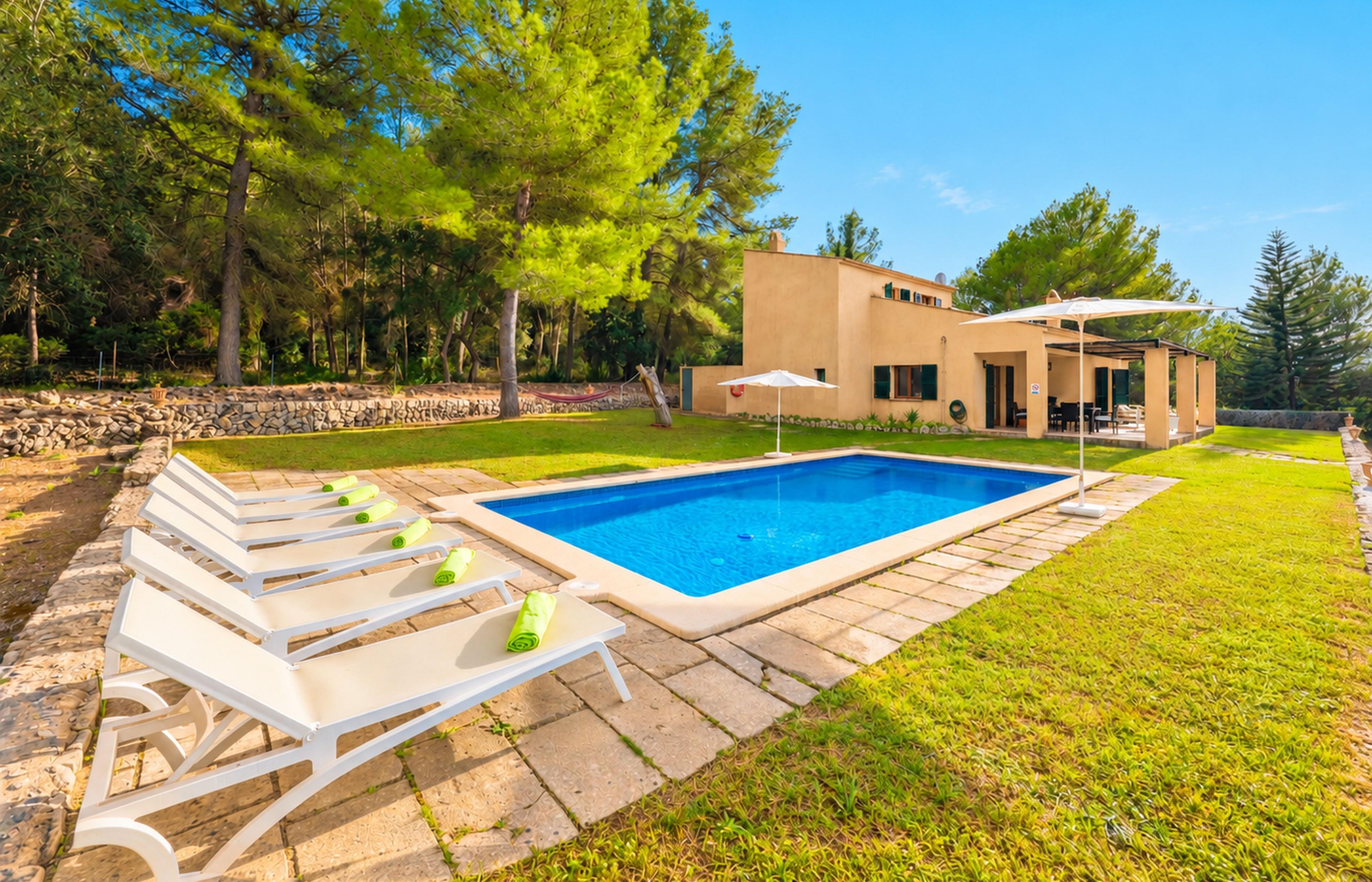 A modern house with a swimming pool, outdoor seating, and a stone wall.