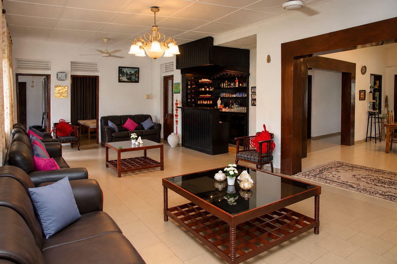 A spacious living area with leather sofas, a coffee table, and a bar area with shelves of bottles.