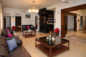 A spacious living area with leather sofas, a coffee table, and a bar area with shelves of bottles. - 4-bedroom house in Negombo close to the Airport (Negombo)