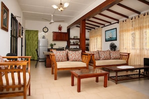 A living room with wooden furniture, a dining table, and a kitchen in the background. - 4-bedroom house in Negombo close to the Airport (Negombo)