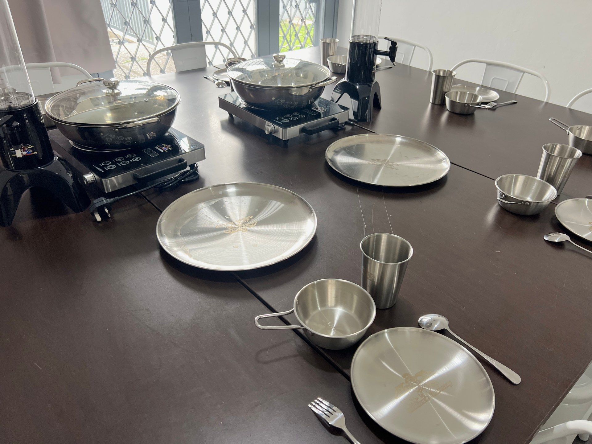 A dining table with various kitchenware, including plates, bowls, and a kettle.