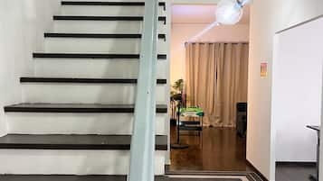 A staircase with alternating black and white steps, a hallway with a ceiling light fixture, and a room with a plant and a Snooker table.