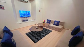 A modern living room with a flat-screen TV, a coffee table, and a sofa set.