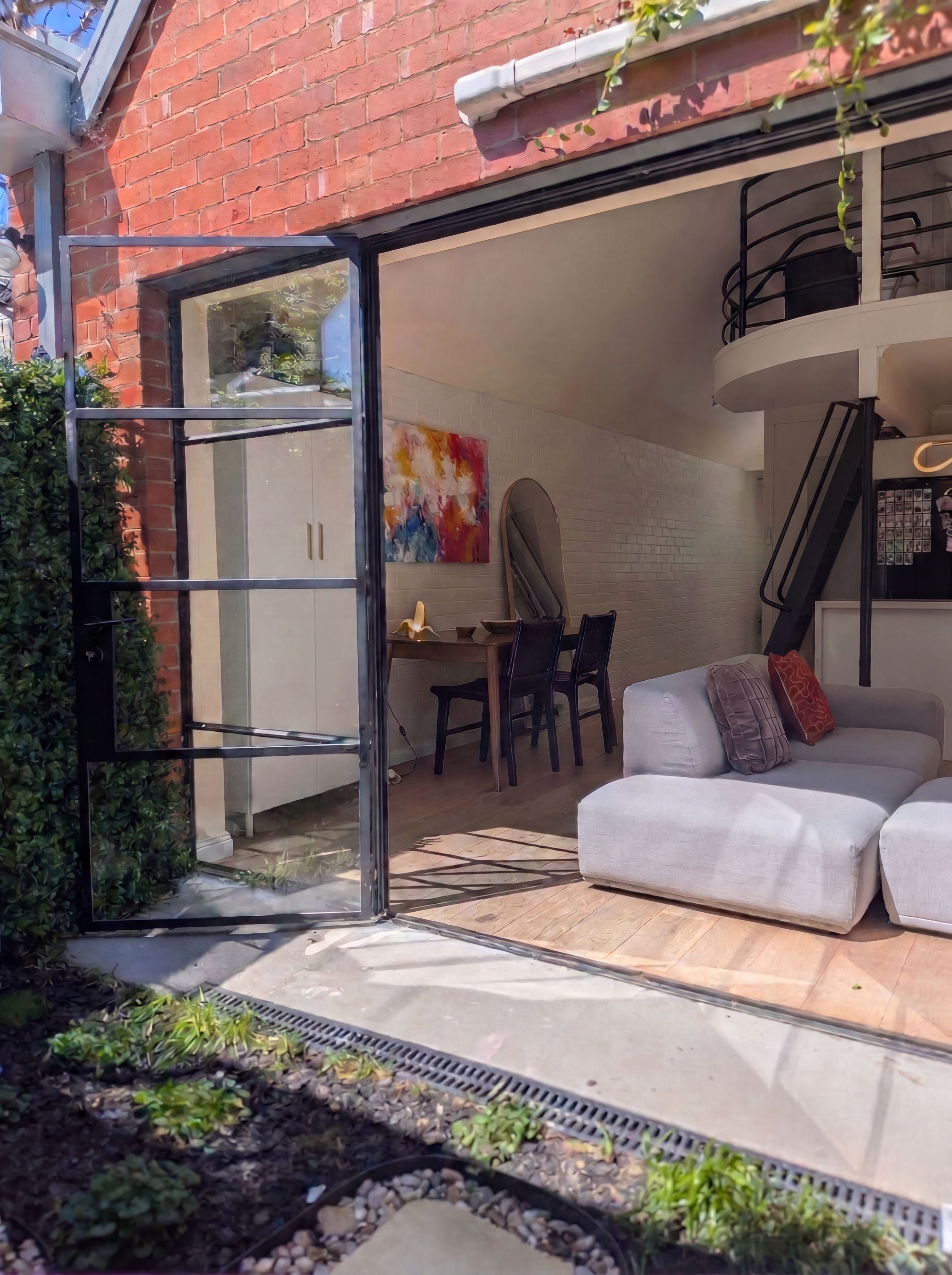A modern interior with a sofa, a dining table, and a staircase.