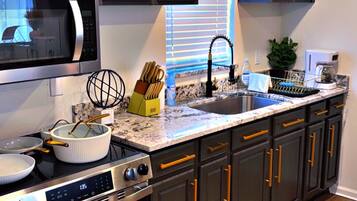 A modern kitchen with dark cabinetry, stainless steel appliances, and a marble countertop.