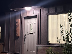 Ein Haus mit einer weißen Tür, einem Fenster mit Blick und einer Pflanze im Vordergrund.