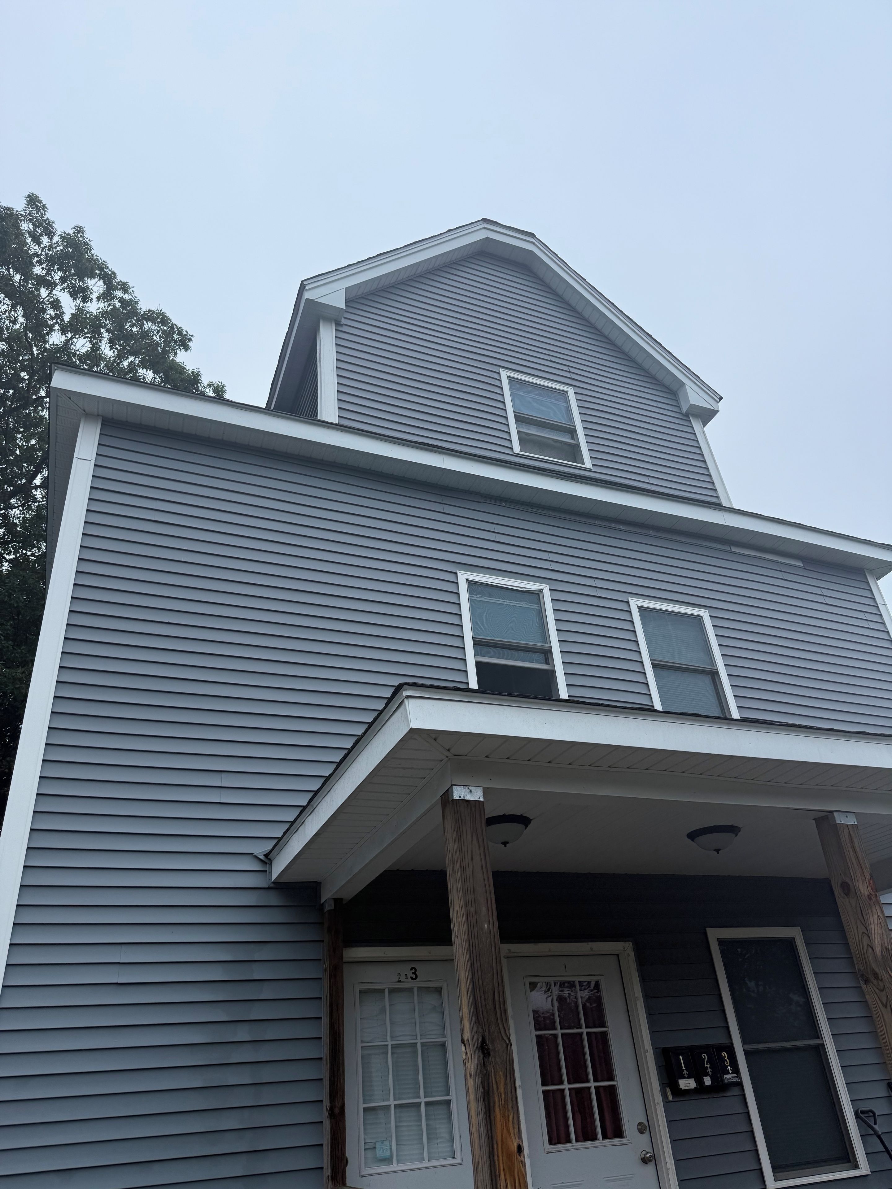 A two-story house with a front porch, a garage door, and a mailbox.