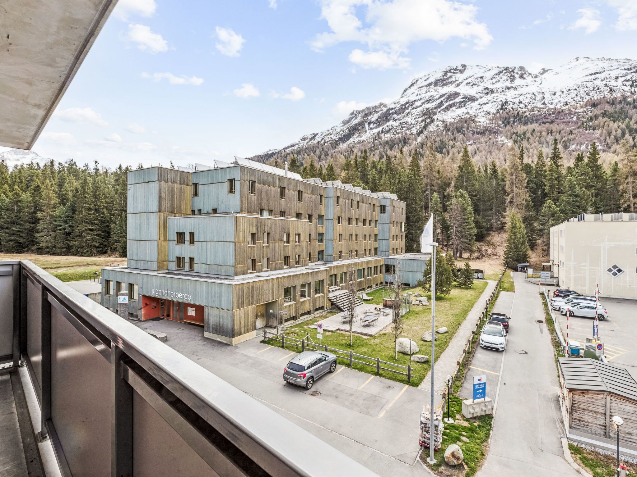 Un hotel de varios pisos con diseño moderno, situado en una zona montañosa con vistas a picos nevados.