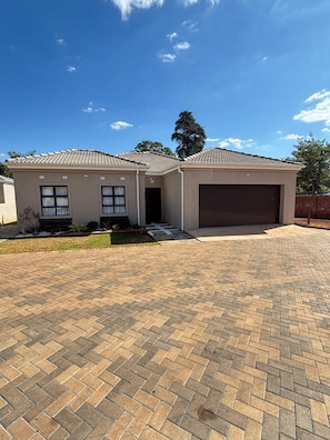 Ein zweistöckiges Haus mit Garage, befestigter Auffahrt und einem kleinen Garten.