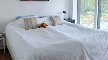 A bedroom with a large bed, a nightstand, a lamp, and a painting on the wall.