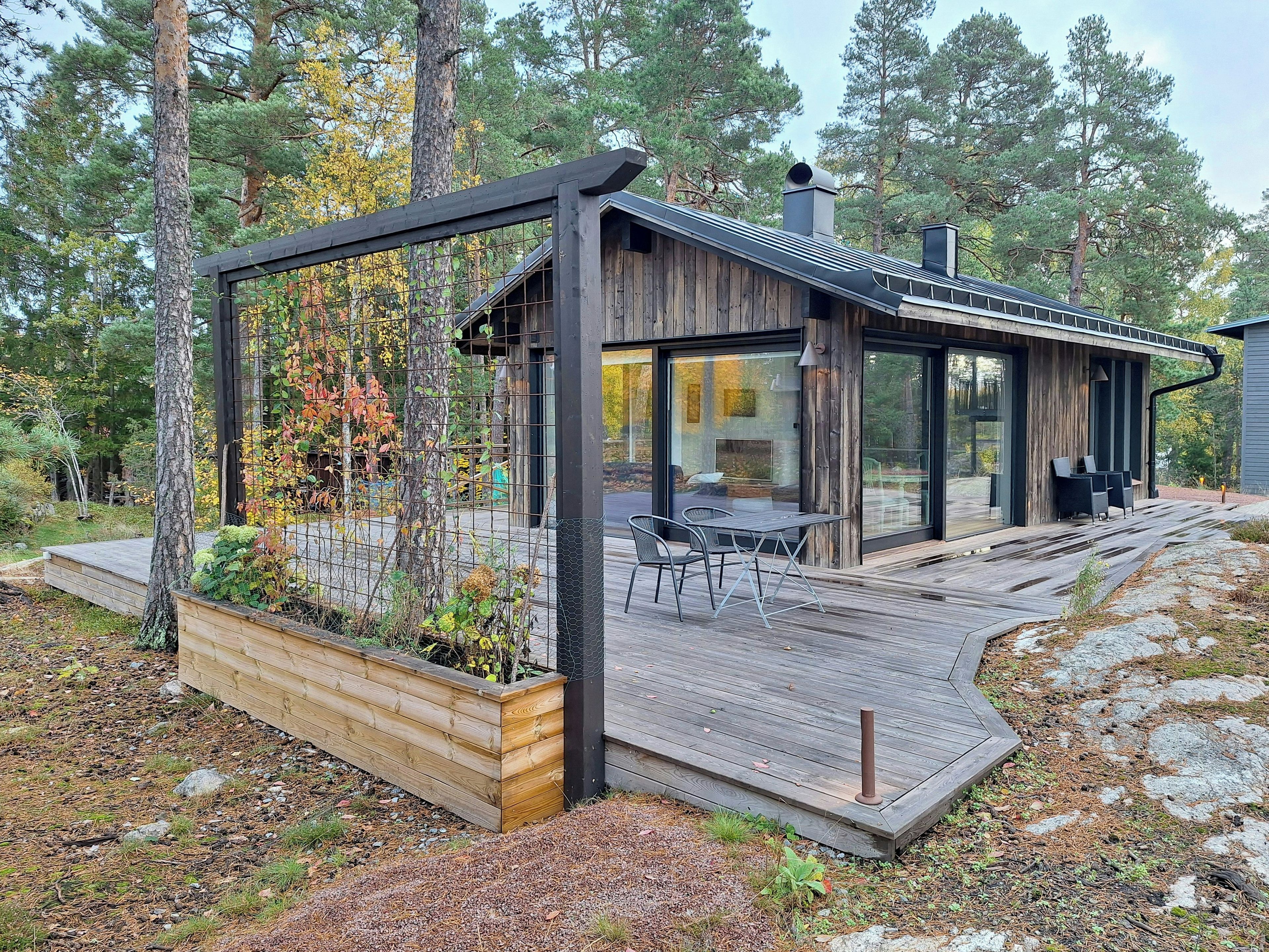 A modern cabin with a deck, a dining area, and a large window.