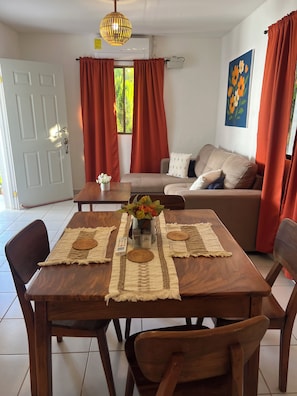 Un comedor con una mesa de madera, sillas, un florero con flores y un cuadro en la pared.
