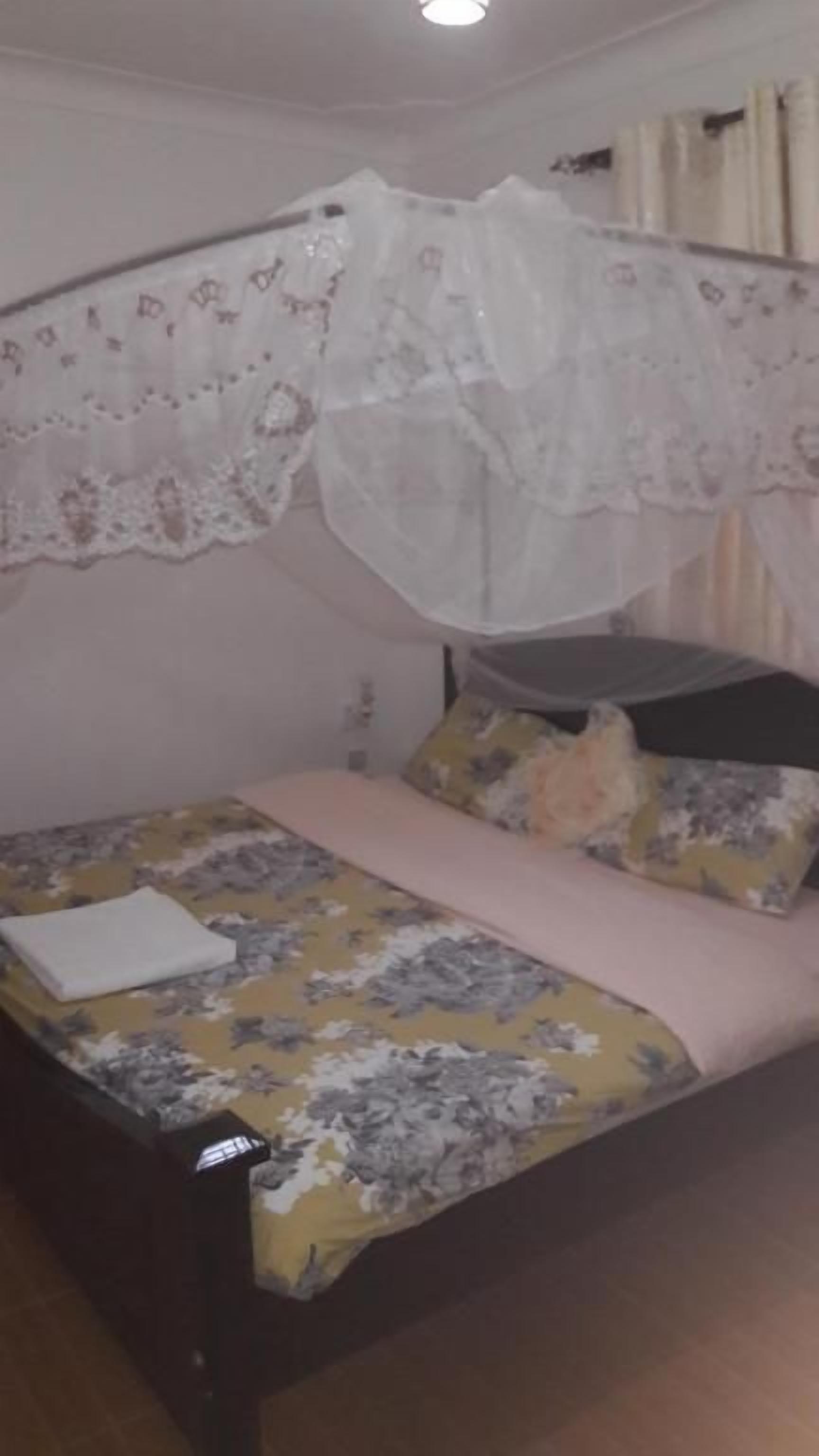 A bed with a floral bedspread, a white pillow, and a canopy with lace detailing.