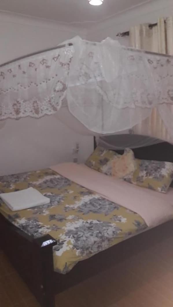 A bed with a floral bedspread, a white pillow, and a canopy with lace detailing.