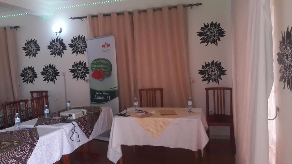 A room with two tables, chairs, a banner, and decorative wall art.