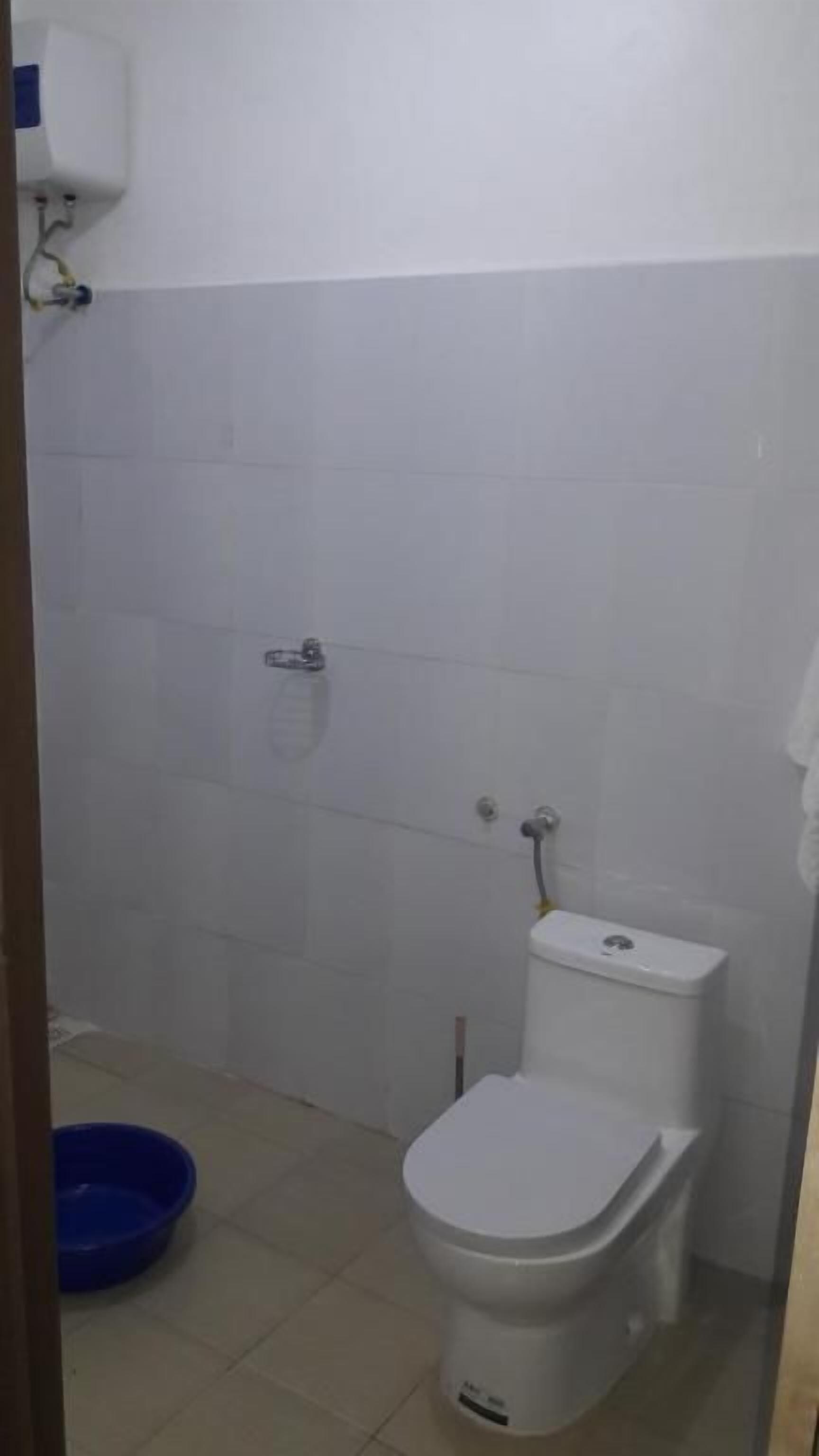 A small, clean bathroom with a toilet, a bidet, and a blue basin.