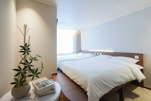 A hotel room with two beds, a bedside table with a book and a plant, and a window with curtains. - Gem Hostel Seoul (jung-gu)